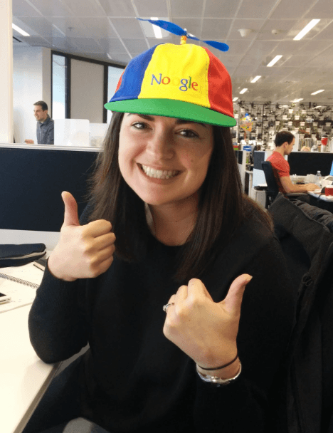 Meg Smith wearing a Noogler hat, a big smile and two thumbs up.